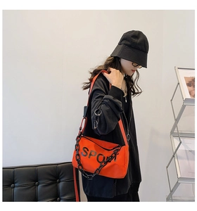 Détail du sac bandoulière orange en nylon avec lettrage sport noir et chaîne épaisse