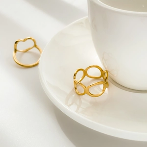 Detail of gold hollow heart and geometric oval rings on white ceramic plate