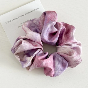 Detailed view of large tie-dye satin scrunchie with pink and purple marble texture