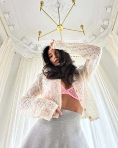Detail shot of cream hollow-out knit cardigan with delicate crochet texture and round buttons