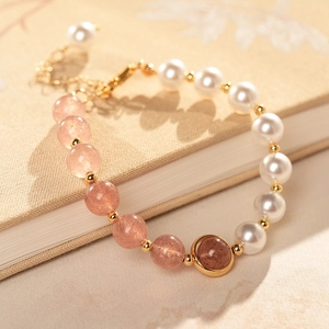 Detail of strawberry quartz and pearl beaded bracelet with gold spacers on book
