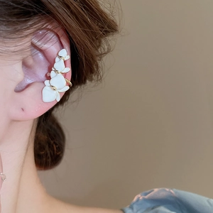 Detail of gold-plated white orchid ear cuff shown in close-up on a model's ear