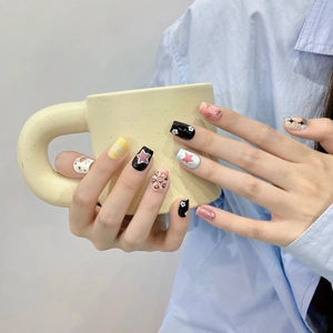 Handmade press-on nails with colorful hand-painted stars and rhinestones on a coffee cup