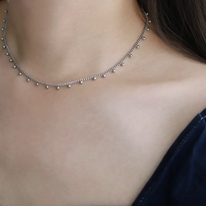 Close-up of a silver beaded chain necklace elegantly worn on a woman's collarbone