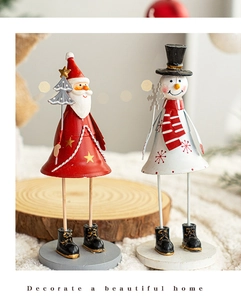 Detailed view of hand-painted iron Santa and Snowman ornaments on rustic wood base