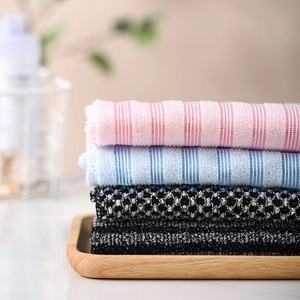 Japanese style long exfoliating back scrubber towels in various striped patterns on a wood tray