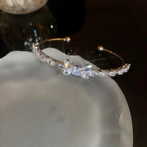 Macro shot of rose gold open bangle with bow motif and shimmering cubic zirconia stones