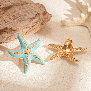 Blue enamel starfish ring in gold finish on a sandy beach setting with ocean theme