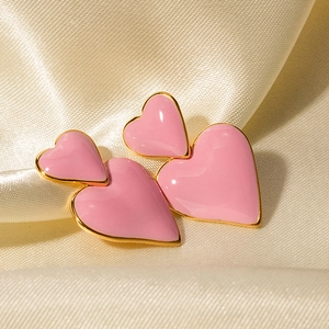 Dettaglio di orecchini a cuore rosa con bordi in oro 18k su tessuto di seta beige