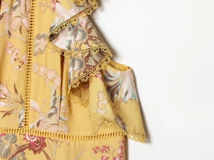 Detalle de vestido floral amarillo con ribetes de encaje y textura de punto calado