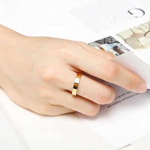 Minimalist golden stainless steel ring with mirror finish worn in a stylish setting