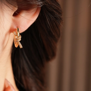 Close-up of 18k gold plated knotted hoop earrings with pave cubic zirconia on ear