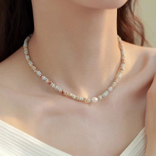 Detail of freshwater pearl necklace with light blue and gold beads on a model