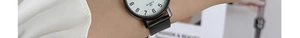 Close-up of minimalist quartz watch with white dial and black strap worn on the wrist