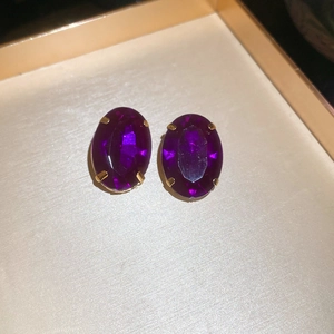 Close-up of vintage oval purple gemstone earrings set in an elegant gold metal frame