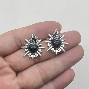 Retro gothic black enamel heart pendant with silver sunburst flame detail on hand