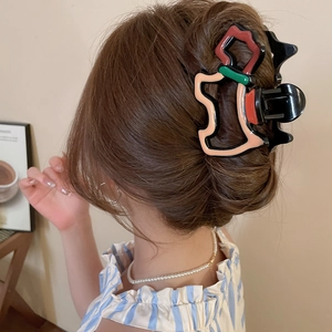 Détail d'une pince à cheveux en acrylique colorée en forme de caniche portée avec style épuré