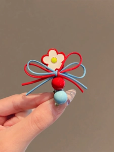 Détail de pince à fleurs avec nœuds rouges et bleus et breloques en perles colorées