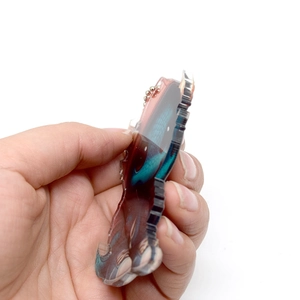 Side view of acrylic dragon pendant showing clear thickness and silver bead chain