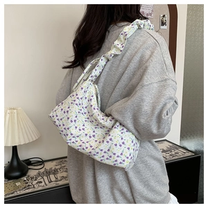 Floral shoulder bag with purple patterns and pleated strap shown on model's back
