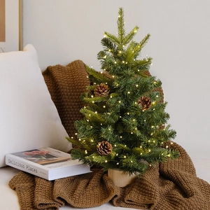 Mini tabletop Christmas tree with warm LED lights, pine cones, and a wooden base decor