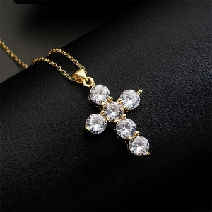Classic gold cross pendant necklace with round zircon stones on black leather background