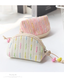 Close-up of woven mini coin purses in beige and pink with colorful embroidery and bead zipper