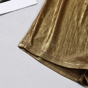 Detail of metallic gold pleated skirt showing vertical texture and fine hem stitching