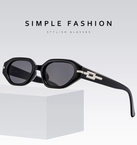 Detail shot of black retro cat-eye sunglasses with silver geometric accents on a pedestal
