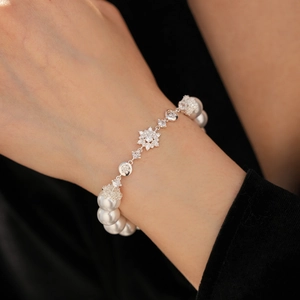 Détail d'un élégant bracelet en perles avec un charme flocon de neige serti de cristaux