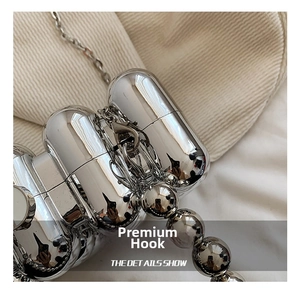 Macro shot of high-polish silver metal hook and chain detail on acrylic dinner bag