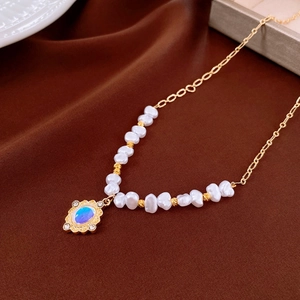 Macro detail of vintage gold pendant necklace with pearl beads and blue-purple stone