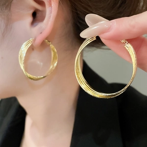 Détail de créoles multicouches entrelacées plaquées or 18 carats sur modèle et à la main