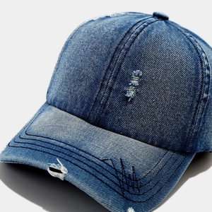 Close-up of distressed denim baseball cap with vintage worn details and black stitching