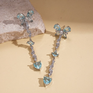 Detail of silver drop earrings featuring blue zircon butterfly and heart fringe accents