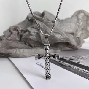 Detailed close-up of textured silver stainless steel cross pendant on box chain necklace