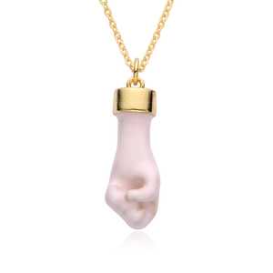 Detail view of pink and white crystal fist pendant with elegant gold chain necklace