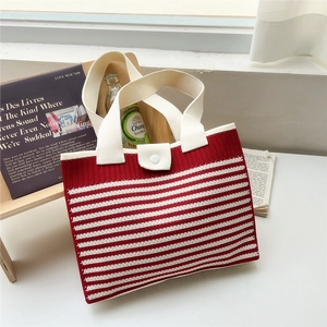 Close-up of red striped knit tote bag with beige handle and white button closure detail
