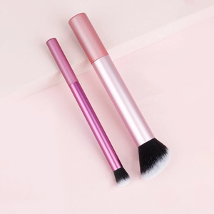 Detail of pink makeup brushes with dual-tone synthetic bristles on a geometric stand