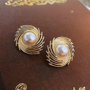 Macro shot of vintage gold spiral pearl earrings resting on a classic book cover