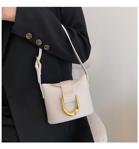 Close-up of minimalist cream leather underarm bag with large gold U-shaped metal clasp