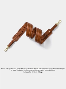 Detail of brown crocodile pattern wide shoulder strap with golden metal swivel hooks