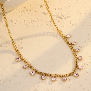 Detail of gold chunky chain necklace with pink pear-shaped crystal pendants on stone