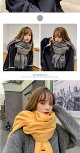 Detail of dark gray and yellow cashmere-feel scarves with fringed edges for winter