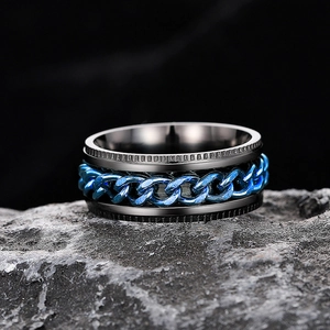 Macro shot of black spinner ring with blue chain inlay on textured stone
