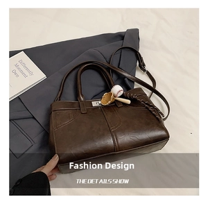 Détail du sac à main rétro en cuir marron foncé avec breloque baseball et fermoir métal