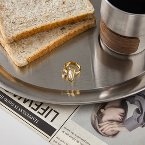 Detailed close-up of 18K gold stainless steel open ring with clear zircon on a metal tray