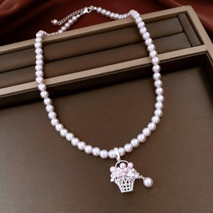 Détail d'un collier de perles avec un pendentif panier à fleurs vintage sur plateau