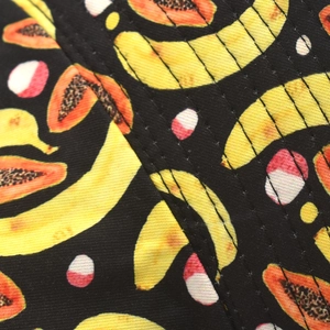 Close-up of tropical banana and papaya prints on black fabric with neat stitching details