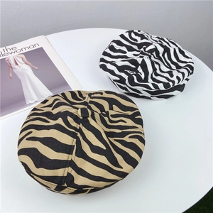 Dettaglio di berretti in cotone con stampa zebra e tigre su tavolo con rivista di moda